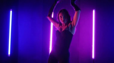 Neon ışıklarının altında dans eden kadın silueti. Canlı neon ışıklı dans pisti ve hareket halindeki bir kadın. Karanlık odada neon parıltısıyla enerjik bir dans gösterisi. Kendinden geçmiş kadın dansçı. Siyah elbiseli zarif bayan parlak neon ışıkların önünde poz veriyor..