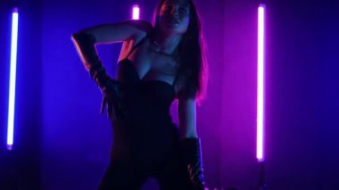 Neon ışıklarının altında dans eden kadın silueti. Canlı neon ışıklı dans pisti ve hareket halindeki bir kadın. Karanlık odada neon parıltısıyla enerjik bir dans gösterisi. Kendinden geçmiş kadın dansçı. Siyah elbiseli zarif bayan parlak neon ışıkların önünde poz veriyor..