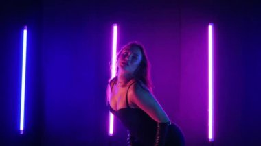 Neon ışıklarının altında dans eden kadın silueti. Canlı neon ışıklı dans pisti ve hareket halindeki bir kadın. Karanlık odada neon parıltısıyla enerjik bir dans gösterisi. Kendinden geçmiş kadın dansçı. Siyah elbiseli zarif bayan parlak neon ışıkların önünde poz veriyor..