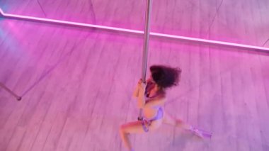 Bir kadın direk dansı yapıyor. Aynalarla dolu bir odada yapılan şehvetli dans hareketleri. Yansıtıcı yüzeyleri olan bir odada direğin üzerinde dönen zarif bir dansçı. Hareketli zarafet: kadın aynalarla çevrili bir direk dansı yapıyor..