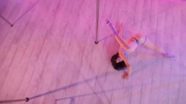 Bir kadın direk dansı yapıyor. Aynalarla dolu bir odada yapılan şehvetli dans hareketleri. Yansıtıcı yüzeyleri olan bir odada direğin üzerinde dönen zarif bir dansçı. Hareketli zarafet: kadın aynalarla çevrili bir direk dansı yapıyor..