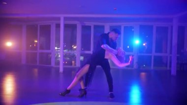 Canlı bir partide zarif bir şekilde tango yapan bir erkek ve kadın. Kizomba 'nın tutkusuna kapılmış iki dansçı. Tango kucaklaşmasında zarif hareket eden bir çift. Bir erkek ve kadın arasında büyüleyici bir dans anı. Gece diskosu partisinde. Aşık dansçılar