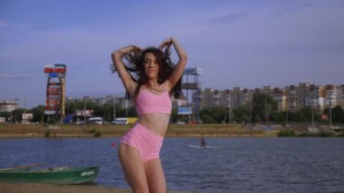 Sahilde dans eden seksi kız. Güzel bir kadın kalçasıyla kumda dans eder. Bikinili seksi kadın. Bikinili genç bir kadın kumların üzerinde enerjik bir dans ediyor..