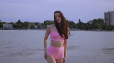 Sahilde dans eden seksi kız. Güzel bir kadın kalçasıyla kumda dans eder. Bikinili seksi kadın. Bikinili genç bir kadın kumların üzerinde enerjik bir dans ediyor..