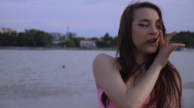 Sahilde dans eden seksi kız. Güzel bir kadın kalçasıyla kumda dans eder. Bikinili seksi kadın. Bikinili genç bir kadın kumların üzerinde enerjik bir dans ediyor..