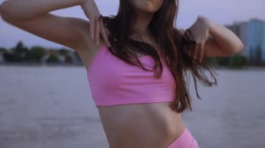 Sahilde dans eden seksi kız. Güzel bir kadın kalçasıyla kumda dans eder. Bikinili seksi kadın. Bikinili genç bir kadın kumların üzerinde enerjik bir dans ediyor..