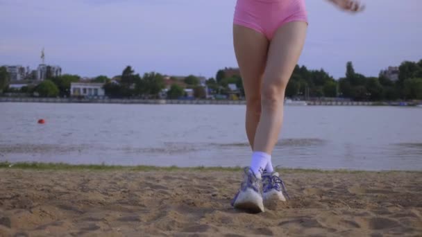 在海滩上跳舞的辣妹 一个漂亮的女人与她的臀部在沙滩上跳舞 穿着比基尼的性感女人一个穿着比基尼的年轻女子正在沙滩上跳着一支充满活力的舞 — 图库视频影像
