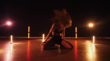 Sexy woman dancing a seductive dance. A dancer girl with a big ass dances erotically in a dark hall. Twerk, high heels, striptease. Sultry woman in lingerie posing in front of a soft light. Sensual pose in lingerie against a glowing backdrop. 