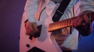 Adamın biri stüdyoda elektro gitar çalıyor. Sürücü gitarist beyaz bir gitarda rock çalar. Stüdyo, renk arkaplanı. Beyaz kapüşonlu müzisyen elektro gitarda çalacak. Beyaz kapüşonlu gitarist elektro gitar çalıyor.. 