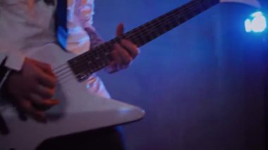 Adamın biri stüdyoda elektro gitar çalıyor. Sürücü gitarist beyaz bir gitarda rock çalar. Stüdyo, renk arkaplanı. Beyaz kapüşonlu müzisyen elektro gitarda çalacak. Beyaz kapüşonlu gitarist elektro gitar çalıyor.. 