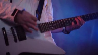 Adamın biri stüdyoda elektro gitar çalıyor. Sürücü gitarist beyaz bir gitarda rock çalar. Stüdyo, renk arkaplanı. Beyaz kapüşonlu müzisyen elektro gitarda çalacak. Beyaz kapüşonlu gitarist elektro gitar çalıyor.. 