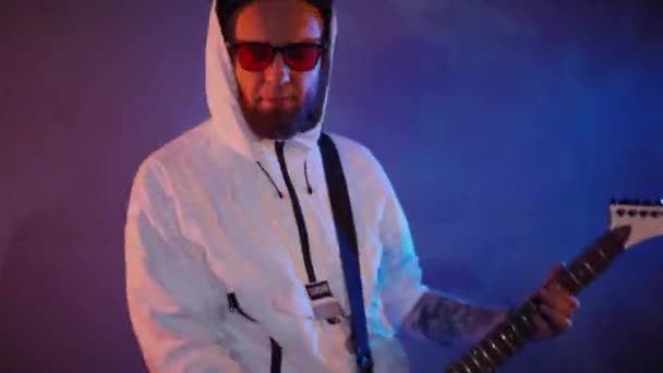一个男人在演播室里弹电吉他 驾驶音乐家吉他手在白色吉他手上玩摇滚 工作室 彩色背景 穿着白色连帽衫的音乐家在弹电吉他 身穿白色连帽衫 弹奏电吉他的吉他手 — 图库视频影像