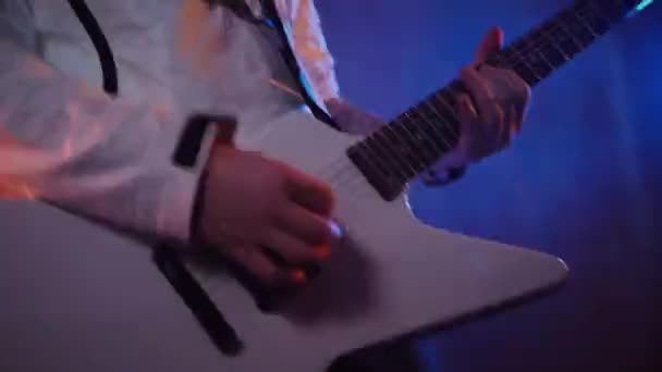 スタジオでエレクトリックギターを演じる男 ドライブミュージシャンのギタリストは白いギターでロックを演じます スタジオ カラーバック エレクトリックギターに詰め込むホワイトフーディのミュージシャン ホワイトフードのギタリスト エレクトリックギター — ストック動画
