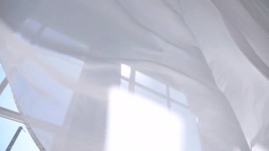 Beyaz şeffaf kumaş rüzgarda dalgalanıyor. Parlak bir stüdyoda uzun beyaz perdeler. Rüzgarda savrulan saf beyaz perdeler. Ağır çekim. Görüntüler. Güneşli bir odada beyaz bir perde yükseliyor. Yumuşak, dalgalı beyaz perde Sakin bir ortamda. 