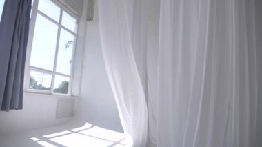 Beyaz şeffaf kumaş rüzgarda dalgalanıyor. Parlak bir stüdyoda uzun beyaz perdeler. Rüzgarda savrulan saf beyaz perdeler. Ağır çekim. Görüntüler. Güneşli bir odada beyaz bir perde yükseliyor. Yumuşak, dalgalı beyaz perde Sakin bir ortamda. 