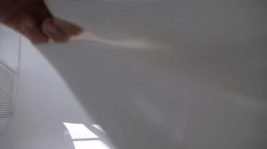 Beyaz şeffaf kumaş rüzgarda dalgalanıyor. Parlak bir stüdyoda uzun beyaz perdeler. Rüzgarda savrulan saf beyaz perdeler. Ağır çekim. Görüntüler. Güneşli bir odada beyaz bir perde yükseliyor. Yumuşak, dalgalı beyaz perde Sakin bir ortamda. 