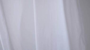 Beyaz şeffaf kumaş rüzgarda dalgalanıyor. Parlak bir stüdyoda uzun beyaz perdeler. Rüzgarda savrulan saf beyaz perdeler. Ağır çekim. Görüntüler. Güneşli bir odada beyaz bir perde yükseliyor. Yumuşak, dalgalı beyaz perde Sakin bir ortamda. 