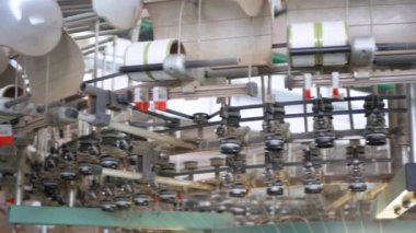 Arabalarda kumaş dokuma. Fabrikadaki ipliklerden kumaş üretimi. Tekstil fabrikası endüstrisi. Kumaş yapan makineler. Fabrikada iplik döndürme makinesi. Endüstriyel iplik dönüyor. Fabrika ortamında otomatik iplik üretimi