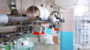 Arabalarda kumaş dokuma. Fabrikadaki ipliklerden kumaş üretimi. Tekstil fabrikası endüstrisi. Kumaş yapan makineler. Fabrikada iplik döndürme makinesi. Endüstriyel iplik dönüyor. Fabrika ortamında otomatik iplik üretimi