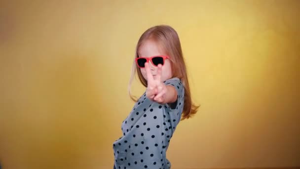 戴太阳镜的小女孩竖起大拇指 快乐的孩子戴着墨镜 竖起大拇指 戴着太阳镜微笑的女孩竖起了大拇指 在阴影中的小女孩 有着积极的姿态 — 图库视频影像