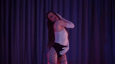 Yüksek topuklularla dans eden seksi kadın. Bir dansçı kız karanlık bir salonda erotik bir şekilde dans eder. Twerk, yüksek topuklar, striptiz, baştan çıkarıcı bir dans. Balık ağı çoraplı baştan çıkarıcı kadın yerde poz veriyor. Balık ağı çoraplı kadın yerde kendine güvenini sergiliyor.. 