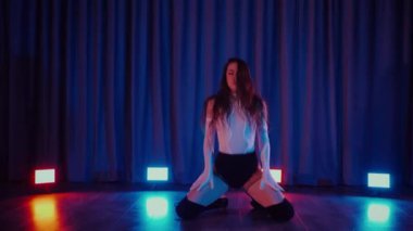 Yüksek topuklularla dans eden seksi kadın. Bir dansçı kız karanlık bir salonda erotik bir şekilde dans eder. Twerk, yüksek topuklar, striptiz, baştan çıkarıcı bir dans. Balık ağı çoraplı baştan çıkarıcı kadın yerde poz veriyor. Balık ağı çoraplı kadın yerde kendine güvenini sergiliyor.. 