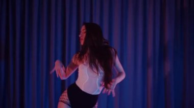 Yüksek topuklularla dans eden seksi kadın. Bir dansçı kız karanlık bir salonda erotik bir şekilde dans eder. Twerk, yüksek topuklar, striptiz, baştan çıkarıcı bir dans. Balık ağı çoraplı baştan çıkarıcı kadın yerde poz veriyor. Balık ağı çoraplı kadın yerde kendine güvenini sergiliyor.. 
