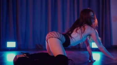 Yüksek topuklularla dans eden seksi kadın. Bir dansçı kız karanlık bir salonda erotik bir şekilde dans eder. Twerk, yüksek topuklar, striptiz, baştan çıkarıcı bir dans. Balık ağı çoraplı baştan çıkarıcı kadın yerde poz veriyor. Balık ağı çoraplı kadın yerde kendine güvenini sergiliyor.. 