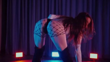 Yüksek topuklularla dans eden seksi kadın. Yavaş çekim. Bir dansçı kız karanlık bir salonda erotik bir şekilde dans eder. Twerk, yüksek topuklar, striptiz, baştan çıkarıcı bir dans. Atmosferik renkli ışık, kulüp, sahne. Balık ağı çoraplı baştan çıkarıcı kadın yerde poz veriyor.. 