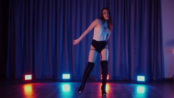 ハイヒールで踊るセクシーな女性 ダンサーの女の子がダークホールでエロチックに踊る ハイヒール ストリップテース 魅惑的なダンス 魚網のストッキングの魅惑的な女性は床にポーズします 魚網のストッキングの女性は床に彼女の自信を欠いている — ストック動画