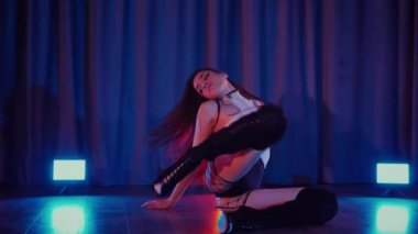 Yüksek topuklularla dans eden seksi kadın. Yavaş çekim. Bir dansçı kız karanlık bir salonda erotik bir şekilde dans eder. Twerk, yüksek topuklar, striptiz, baştan çıkarıcı bir dans. Atmosferik renkli ışık, kulüp, sahne. Balık ağı çoraplı baştan çıkarıcı kadın yerde poz veriyor.. 