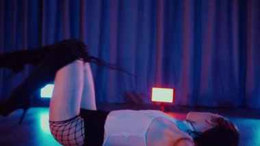 Yüksek topuklularla dans eden seksi kadın. Yavaş çekim. Bir dansçı kız karanlık bir salonda erotik bir şekilde dans eder. Twerk, yüksek topuklar, striptiz, baştan çıkarıcı bir dans. Atmosferik renkli ışık, kulüp, sahne. Balık ağı çoraplı baştan çıkarıcı kadın yerde poz veriyor.. 