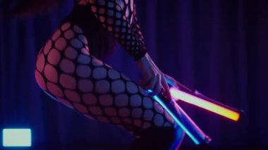 Elinde fenerlerle dans eden seksi bir kadın. Bir dansçı kız karanlık bir salonda erotik bir şekilde dans eder. Yavaş çekim. Twerk, yüksek topuklar, striptiz, baştan çıkarıcı bir dans. Balık ağı çoraplı bir kadın ahşap zeminde boğucu bir poz veriyor..