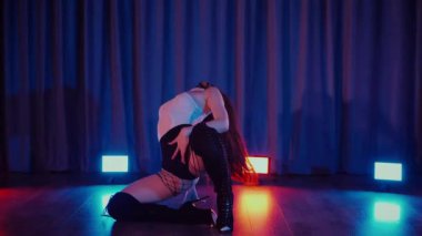 Yüksek topuklularla dans eden seksi kadın. Yavaş çekim. Bir dansçı kız karanlık bir salonda erotik bir şekilde dans eder. Twerk, yüksek topuklar, striptiz, baştan çıkarıcı bir dans. Atmosferik renkli ışık, kulüp, sahne. Balık ağı çoraplı baştan çıkarıcı kadın yerde poz veriyor.. 
