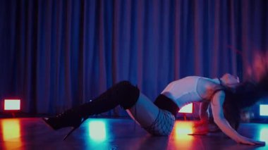 Yüksek topuklularla dans eden seksi kadın. Yavaş çekim. Bir dansçı kız karanlık bir salonda erotik bir şekilde dans eder. Twerk, yüksek topuklar, striptiz, baştan çıkarıcı bir dans. Atmosferik renkli ışık, kulüp, sahne. Balık ağı çoraplı baştan çıkarıcı kadın yerde poz veriyor.. 