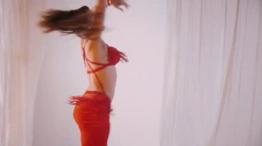 Güzel kız oryantal göbek dansı yapıyor. Kırmızı iç çamaşırlı seksi kadın beyaz bir stüdyoda baştan çıkarıcı bir dans yapıyor. Güzel bir karın ve göğüsler. Kırmızı elbiseli şık bir kadın model. Kırmızı elbiseli zarif bir kadın poz veriyor.. 