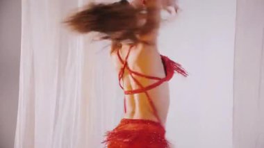 Güzel kız oryantal göbek dansı yapıyor. Kırmızı iç çamaşırlı seksi kadın beyaz bir stüdyoda baştan çıkarıcı bir dans yapıyor. Güzel bir karın ve göğüsler. Kırmızı elbiseli şık bir kadın model. Kırmızı elbiseli zarif bir kadın poz veriyor.. 
