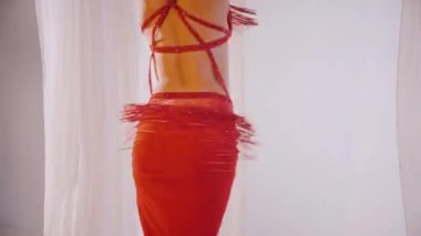 Güzel kız oryantal göbek dansı yapıyor. Kırmızı iç çamaşırlı seksi kadın beyaz bir stüdyoda baştan çıkarıcı bir dans yapıyor. Güzel bir karın ve göğüsler. Kırmızı elbiseli şık bir kadın model. Kırmızı elbiseli zarif bir kadın poz veriyor.. 