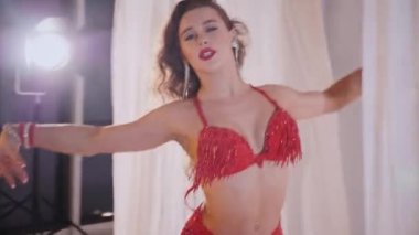 Güzel kız oryantal göbek dansı yapıyor. Kırmızı iç çamaşırlı seksi kadın beyaz bir stüdyoda baştan çıkarıcı bir dans yapıyor. Güzel bir karın ve göğüsler. Kırmızı elbiseli şık bir kadın model. Kırmızı elbiseli zarif bir kadın poz veriyor.. 