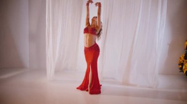 Güzel kız oryantal göbek dansı yapıyor. Ağır çekim. Kırmızı iç çamaşırlı seksi kadın beyaz bir stüdyoda baştan çıkarıcı bir dans yapıyor. Güzel bir karın ve göğüsler. Kırmızı elbiseli şık bir kadın model. Kırmızı elbiseli zarif bir kadın poz veriyor.. 