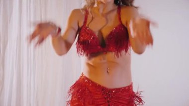 Güzel kız oryantal göbek dansı yapıyor. Ağır çekim. Kırmızı iç çamaşırlı seksi kadın beyaz bir stüdyoda baştan çıkarıcı bir dans yapıyor. Güzel bir karın ve göğüsler. Kırmızı elbiseli şık bir kadın model. Kırmızı elbiseli zarif bir kadın poz veriyor.. 