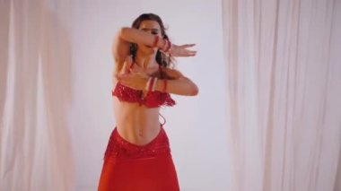 Güzel kız oryantal göbek dansı yapıyor. Ağır çekim. Kırmızı iç çamaşırlı seksi kadın beyaz bir stüdyoda baştan çıkarıcı bir dans yapıyor. Güzel bir karın ve göğüsler. Kırmızı elbiseli şık bir kadın model. Kırmızı elbiseli zarif bir kadın poz veriyor.. 