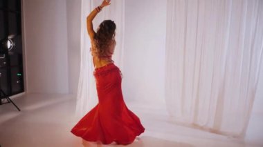 Güzel kız oryantal göbek dansı yapıyor. Ağır çekim. Kırmızı iç çamaşırlı seksi kadın beyaz bir stüdyoda baştan çıkarıcı bir dans yapıyor. Güzel bir karın ve göğüsler. Kırmızı elbiseli şık bir kadın model. Kırmızı elbiseli zarif bir kadın poz veriyor.. 