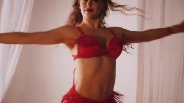 Güzel kız oryantal göbek dansı yapıyor. Ağır çekim. Kırmızı iç çamaşırlı seksi kadın beyaz bir stüdyoda baştan çıkarıcı bir dans yapıyor. Güzel bir karın ve göğüsler. Kırmızı elbiseli şık bir kadın model. Kırmızı elbiseli zarif bir kadın poz veriyor.. 
