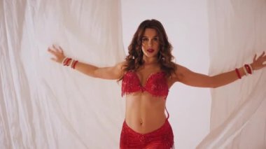 Güzel kız oryantal göbek dansı yapıyor. Ağır çekim. Kırmızı iç çamaşırlı seksi kadın beyaz bir stüdyoda baştan çıkarıcı bir dans yapıyor. Güzel bir karın ve göğüsler. Kırmızı elbiseli şık bir kadın model. Kırmızı elbiseli zarif bir kadın poz veriyor.. 