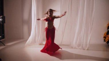 Güzel kız oryantal göbek dansı yapıyor. Ağır çekim. Kırmızı iç çamaşırlı seksi kadın beyaz bir stüdyoda baştan çıkarıcı bir dans yapıyor. Güzel bir karın ve göğüsler. Kırmızı elbiseli şık bir kadın model. Kırmızı elbiseli zarif bir kadın poz veriyor.. 