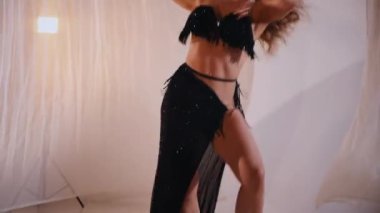 Güzel kız oryantal göbek dansı yapıyor. Siyah göbek dansı kostümlü kadın poz veriyor. Büyüleyici siyah elbiseli kadın dansçı. Koyu renk dansçı kıyafeti içinde zarif bir dansçı. Çarpıcı siyah bir göbek dansı kostümü giymiş bir kadın. yavaş çekim