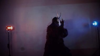 Şeytan canavar dans ediyor. Karanlık bir stüdyoda maskeli gizemli bir adam. Adam siyah bir ceket ve boynuzlu bir maske giymiş. Uzaylı uzaylı. Korkunç.,