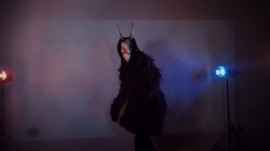 Şeytan canavar dans ediyor. Karanlık bir stüdyoda maskeli gizemli bir adam. Adam siyah bir ceket ve boynuzlu bir maske giymiş. Uzaylı uzaylı. Korkunç.,