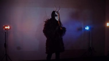 Şeytan canavar flüt çalıyor. Karanlık bir stüdyoda maskeli gizemli bir adam. Adam siyah bir ceket ve boynuzlu bir maske giymiş. Uzaylı uzaylı. Korkunç.,